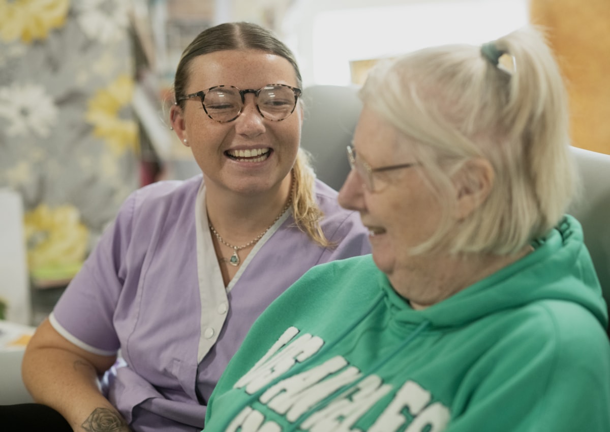 Caregiver and senior woman smiling warmly together